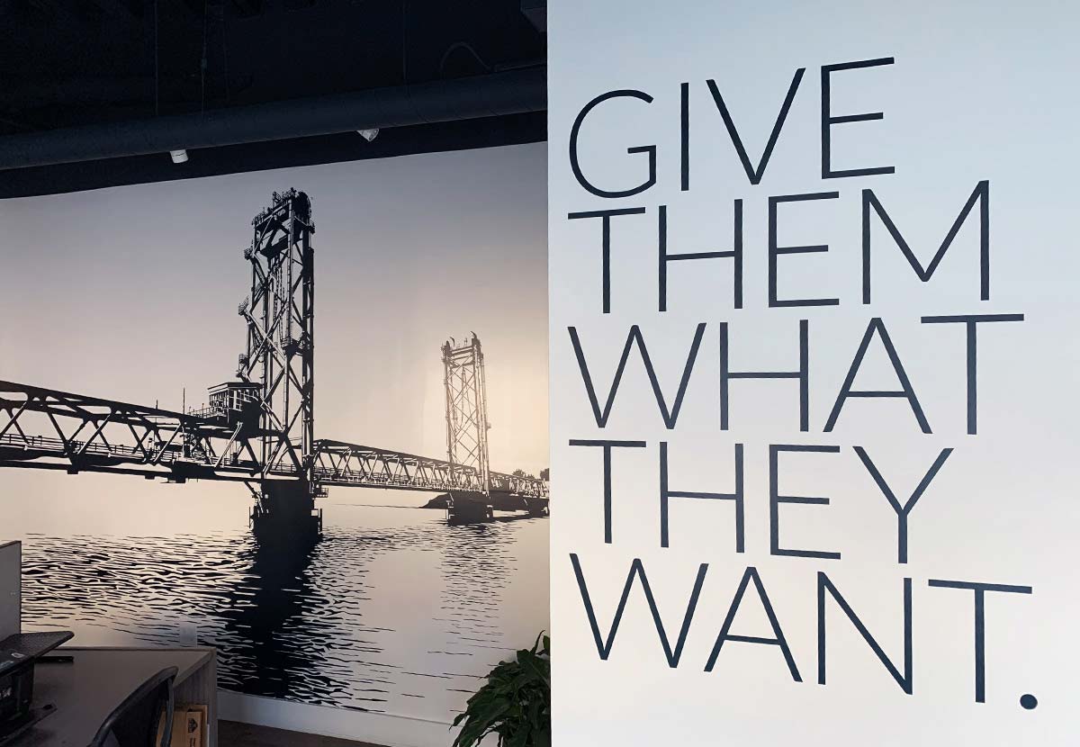 a painted wall with an image of the memorial bridge in portsmouth and the words "give them what they want"