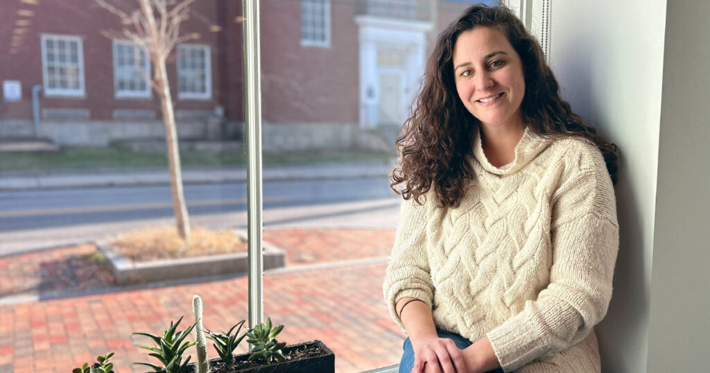 Woman in white sweater on a windowsill smiling